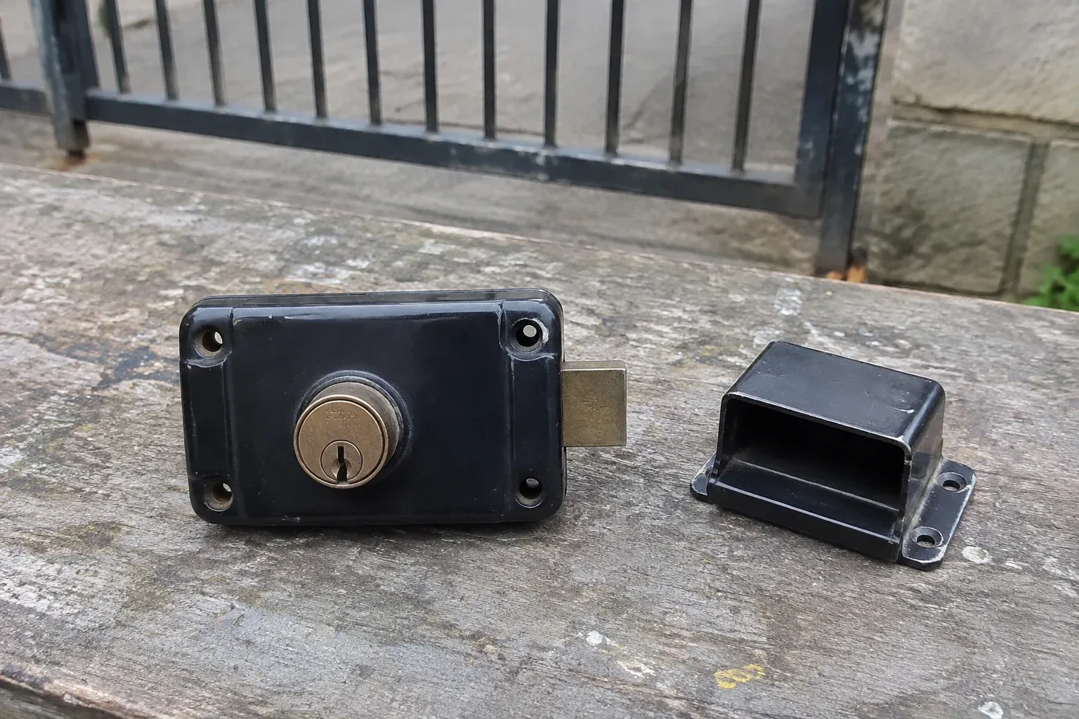 Detached rim gate lock and separate box keeper on an outdoor workbench. — Gate & Building Entry Locks, Milton